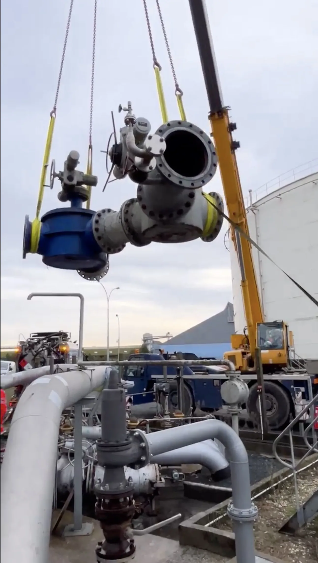 Levage d’une vanne et d’un collecteur à la grue devant un réservoir